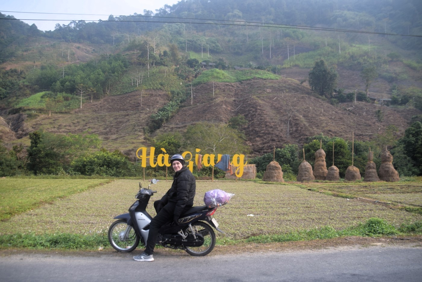 Jake on a motorbike next to the Ha Giang sign